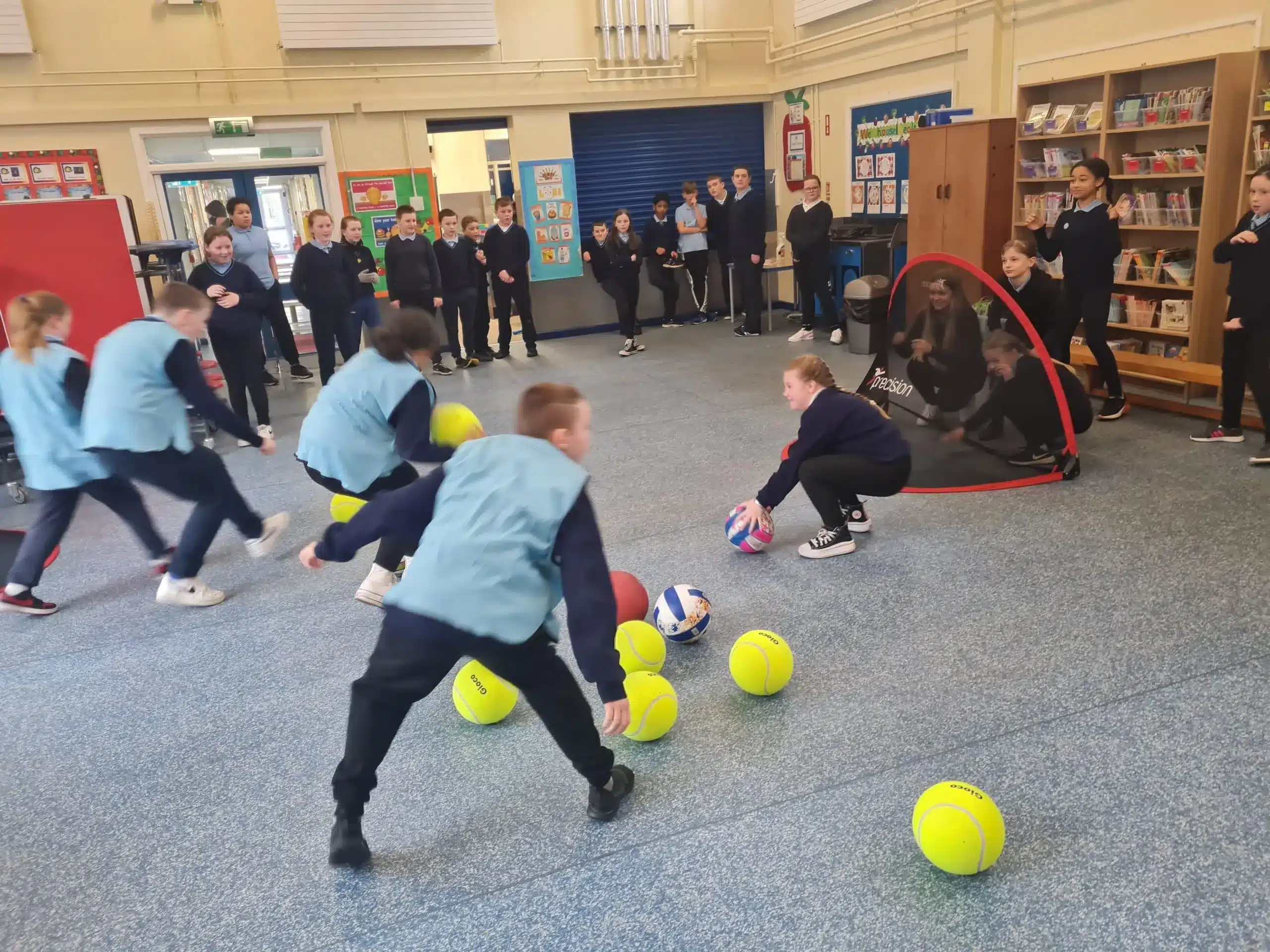 Children playing with yellow balls indoors.